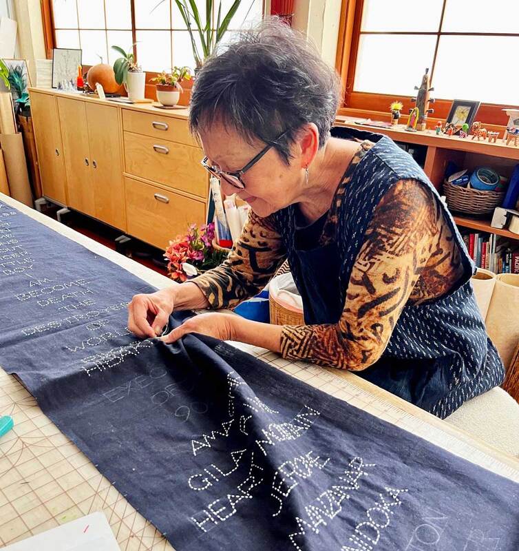 Closeup photo of a woman hand embroidering a dark blue cloth
