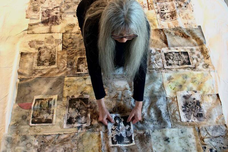 Photo of a woman laying a piece of printed fabric on top of a large collage of fabric rectangles laid across the floor